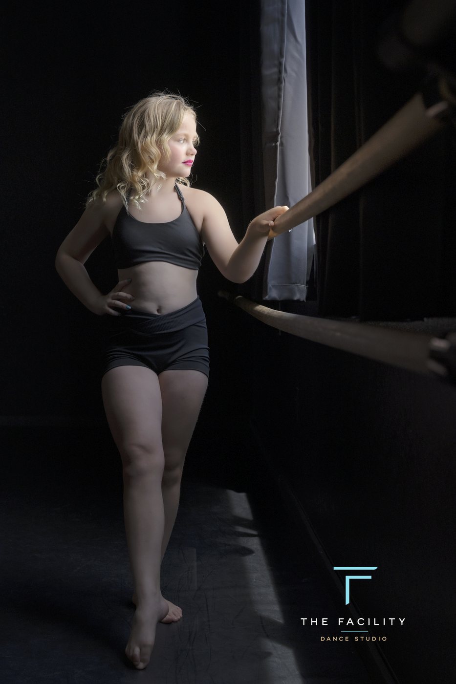 Young dancer with a hand on her hip at the barre